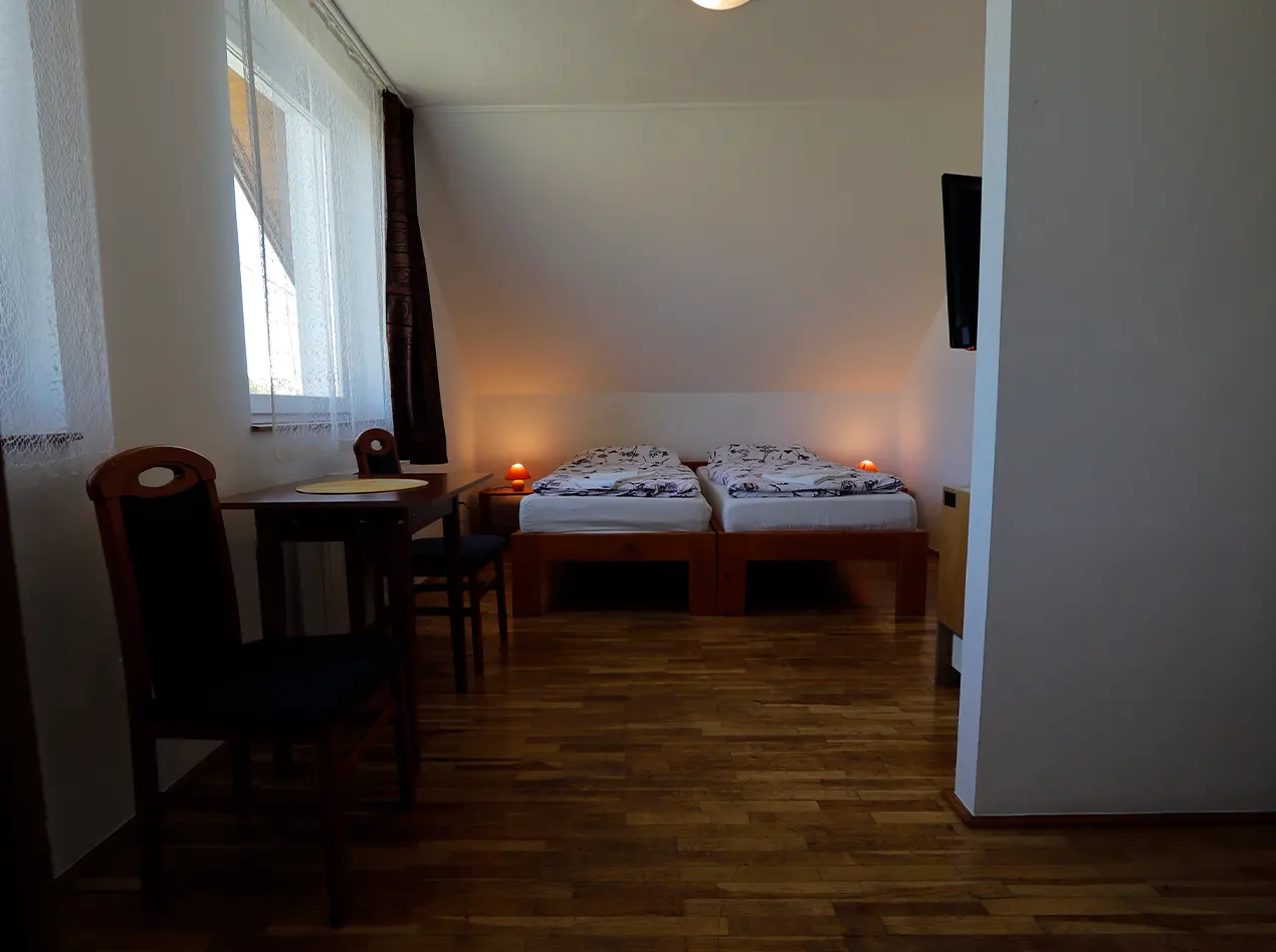 Doppelzimmer im Dachgeschoss mit Tisch und Fernseher im Anna Gästehaus.