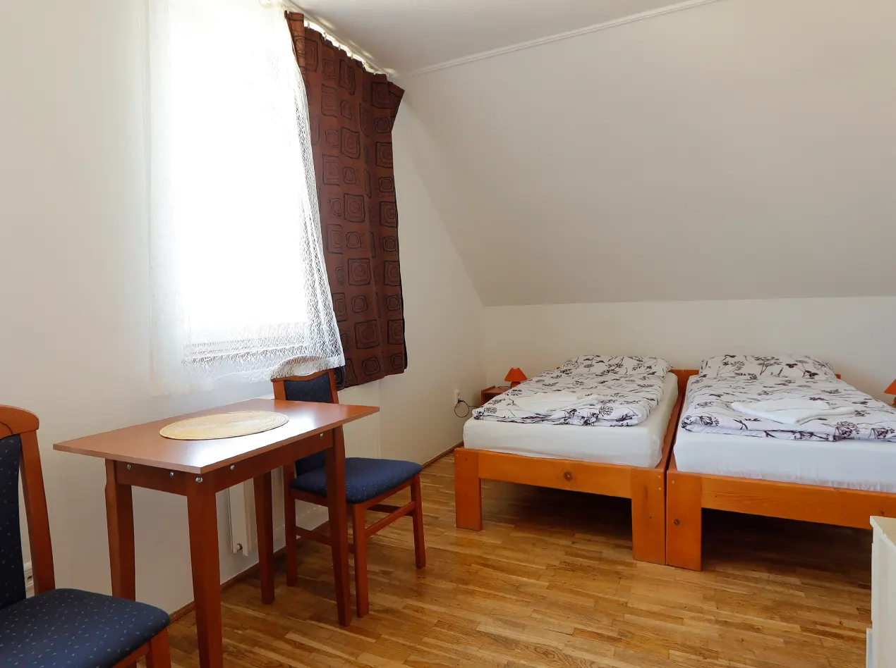 Helles Doppelzimmer mit Tisch und Sitzgelegenheiten im Anna Gästehaus.